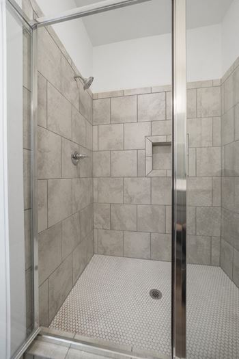 Stand up shower with glass doors, tile walls, and flooring.
